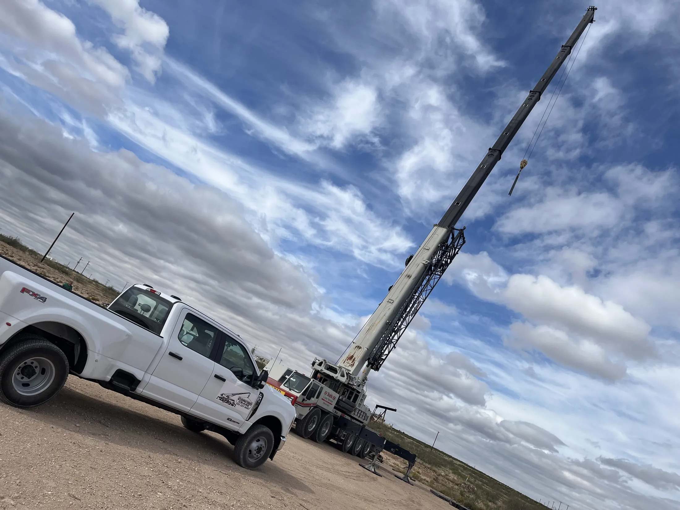 Link-Belt ATC-3210 crane with its boom raised, next to a Concho Crane Co. pickup